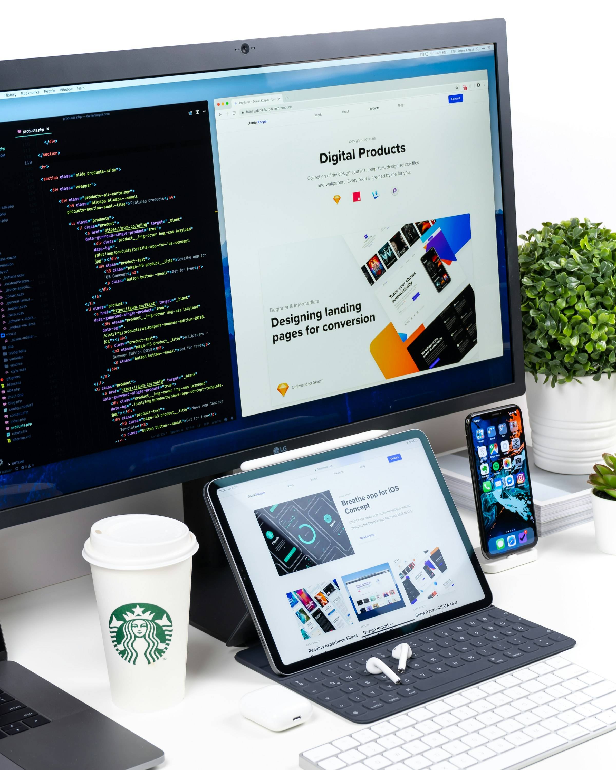 Schreibtisch mit Monitor, Tablet und Smartphone, auf dem Bildschirm Code und der Entwurf einer Landingpage